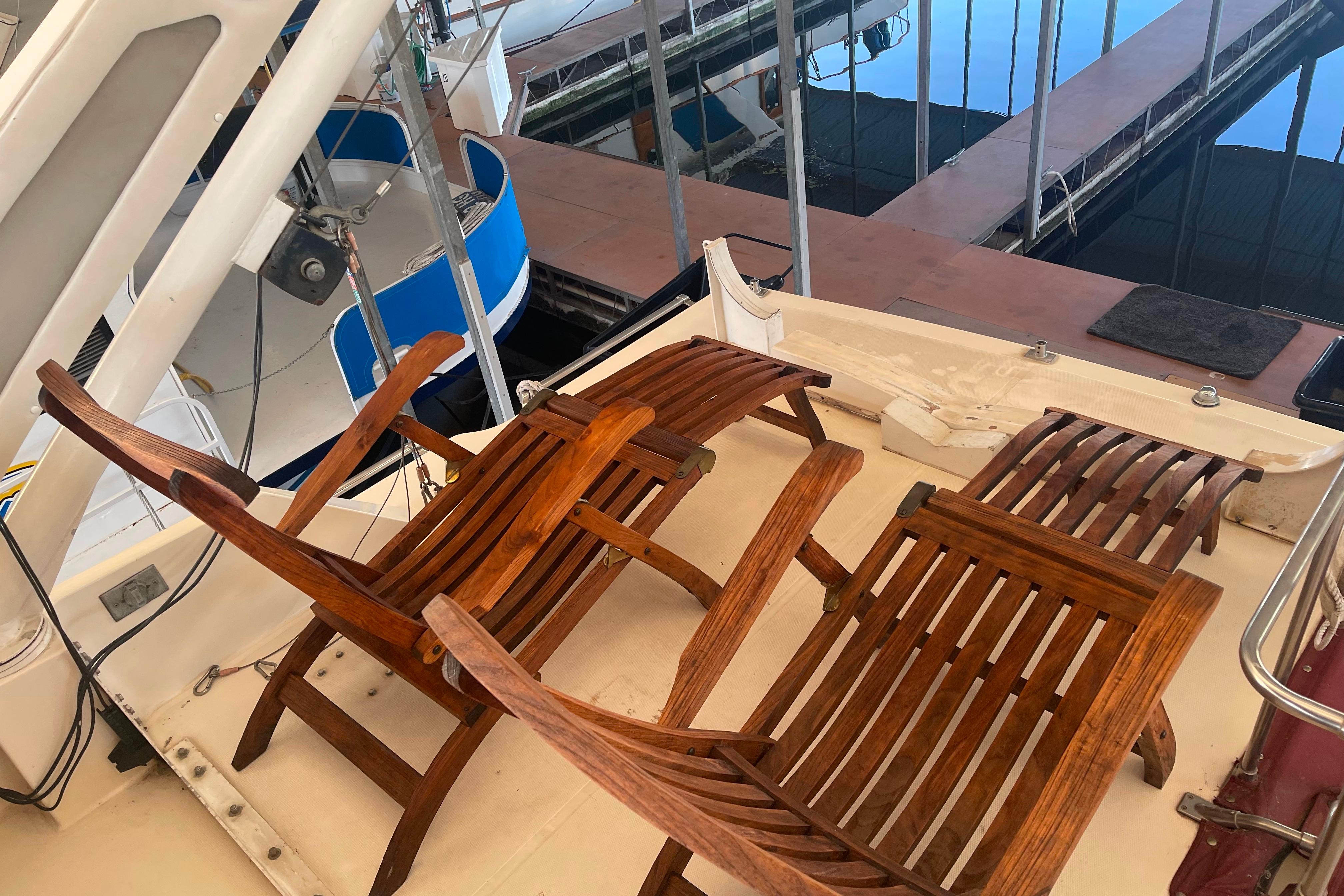 1986 Bayliner 4550 Motoryacht deck with wooden chairs, docked at marina.