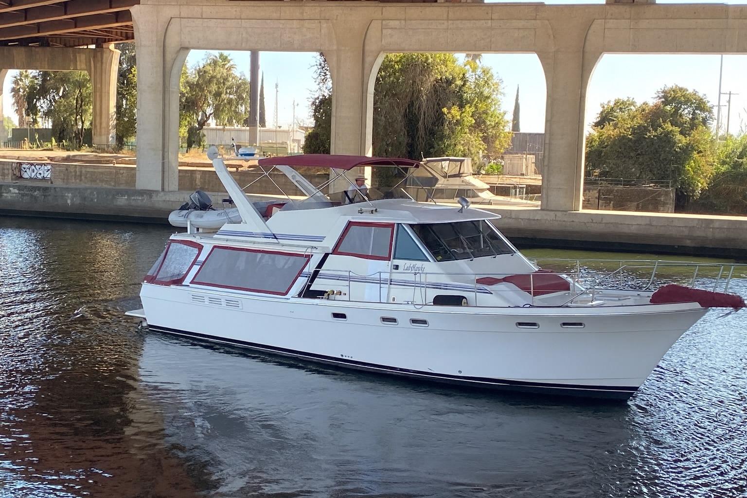 1986 Bayliner 4550 Motoryacht cruising under a bridge on a sunny day.