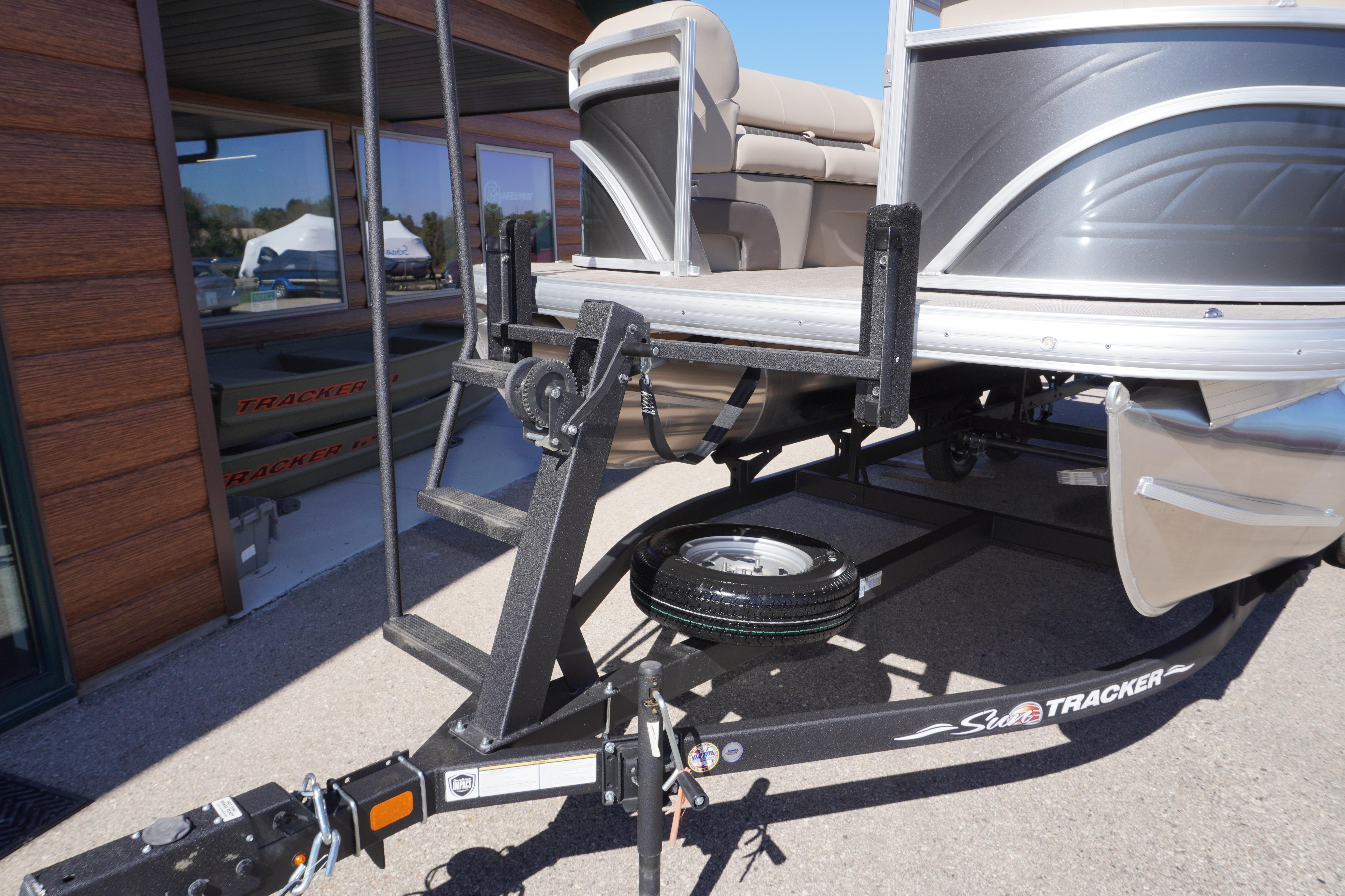 2024 Sun Tracker Party Barge 20 DLX on trailer, parked outside a building.