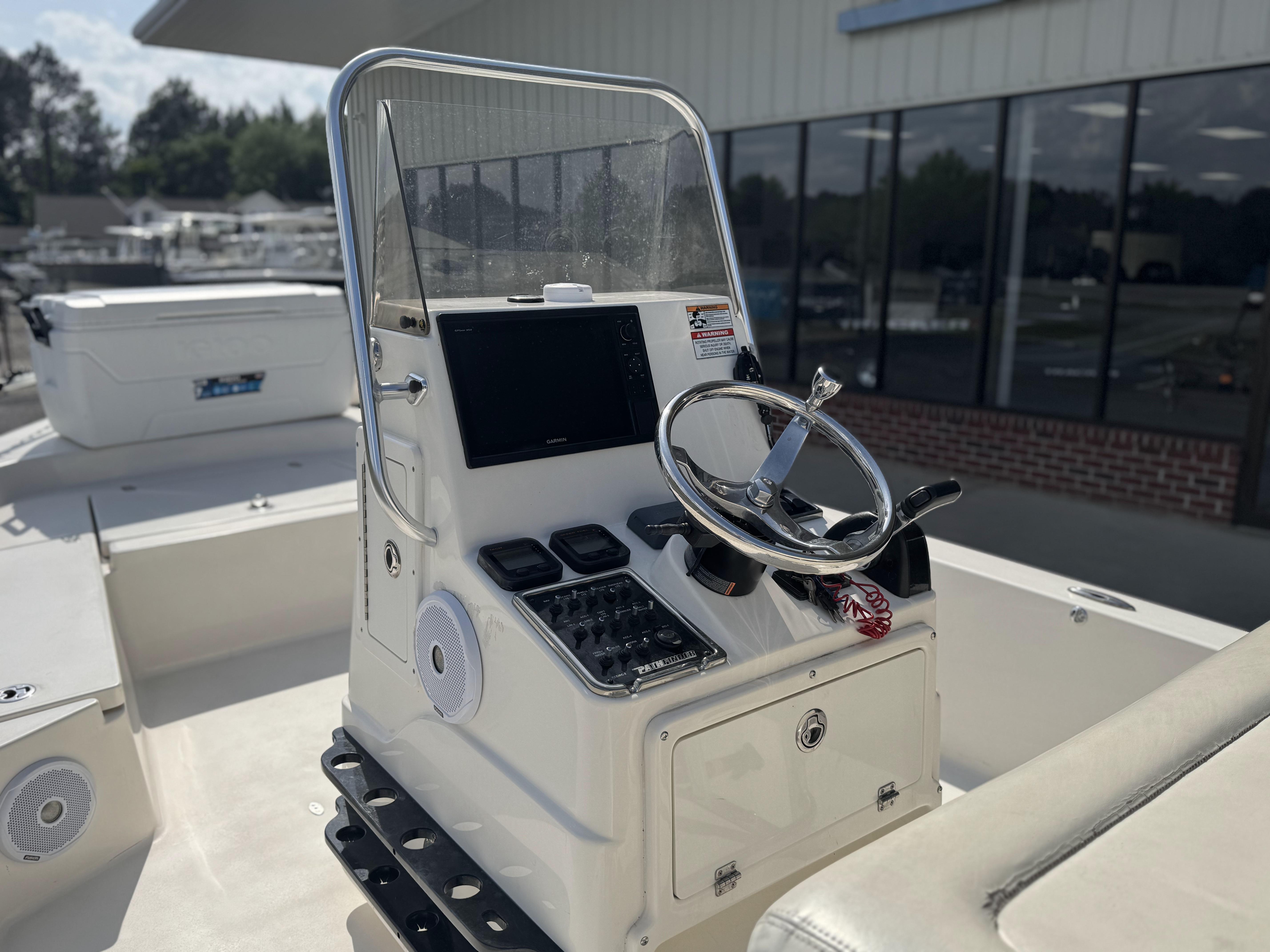 2014 Pathfinder 2200 TRS boat console with steering wheel and controls, docked near a building.