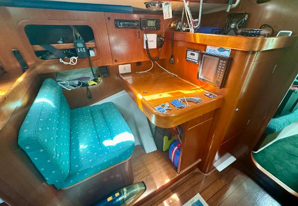 Navigation station in 1996 Beneteau Oceanis 40 CC sailboat with wooden desk and blue chair.