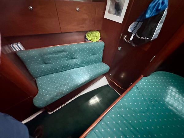 Cozy interior of 1996 Beneteau Oceanis 40 CC sailboat with teal seating and wooden cabinetry.