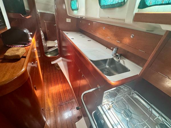 Interior of 1996 Beneteau Oceanis 40 CC yacht, featuring wooden cabinetry and compact kitchen area.