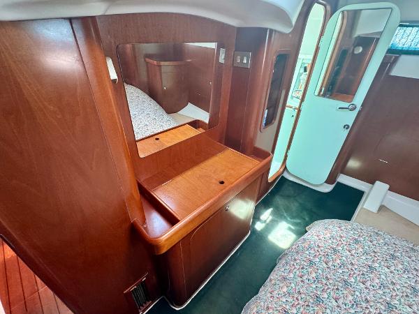 Interior of 1996 Beneteau Oceanis 40 CC yacht with wooden cabinetry and cozy bedding.