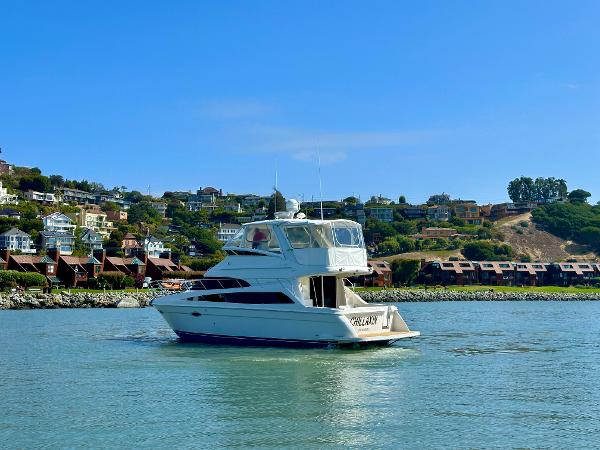 2008 Carver 43 Super Sport yacht cruising near coastal homes under clear blue skies.