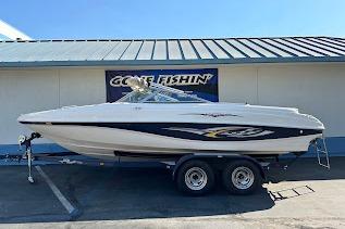 2002 Rinker 212 Captiva boat on trailer, parked outside a building.