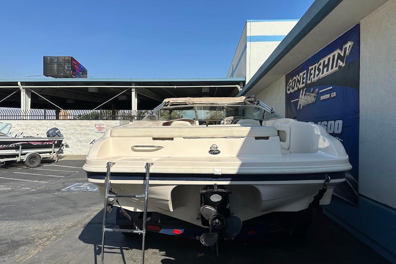 2002 Rinker 212 Captiva boat parked at dealership with ladder and propeller visible.