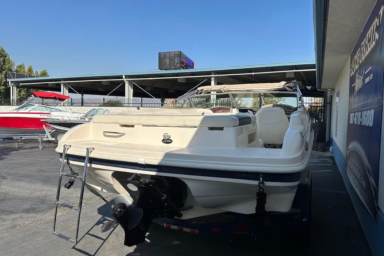 2002 Rinker 212 Captiva boat with ladder, parked outdoors near dealership.