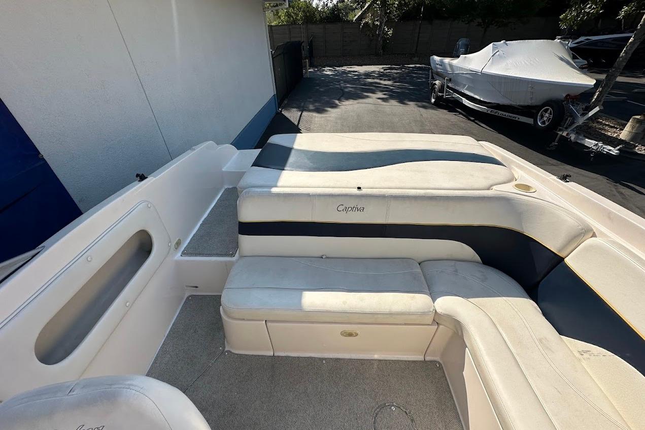 2002 Rinker 212 Captiva boat interior with cushioned seating and carpeted flooring.