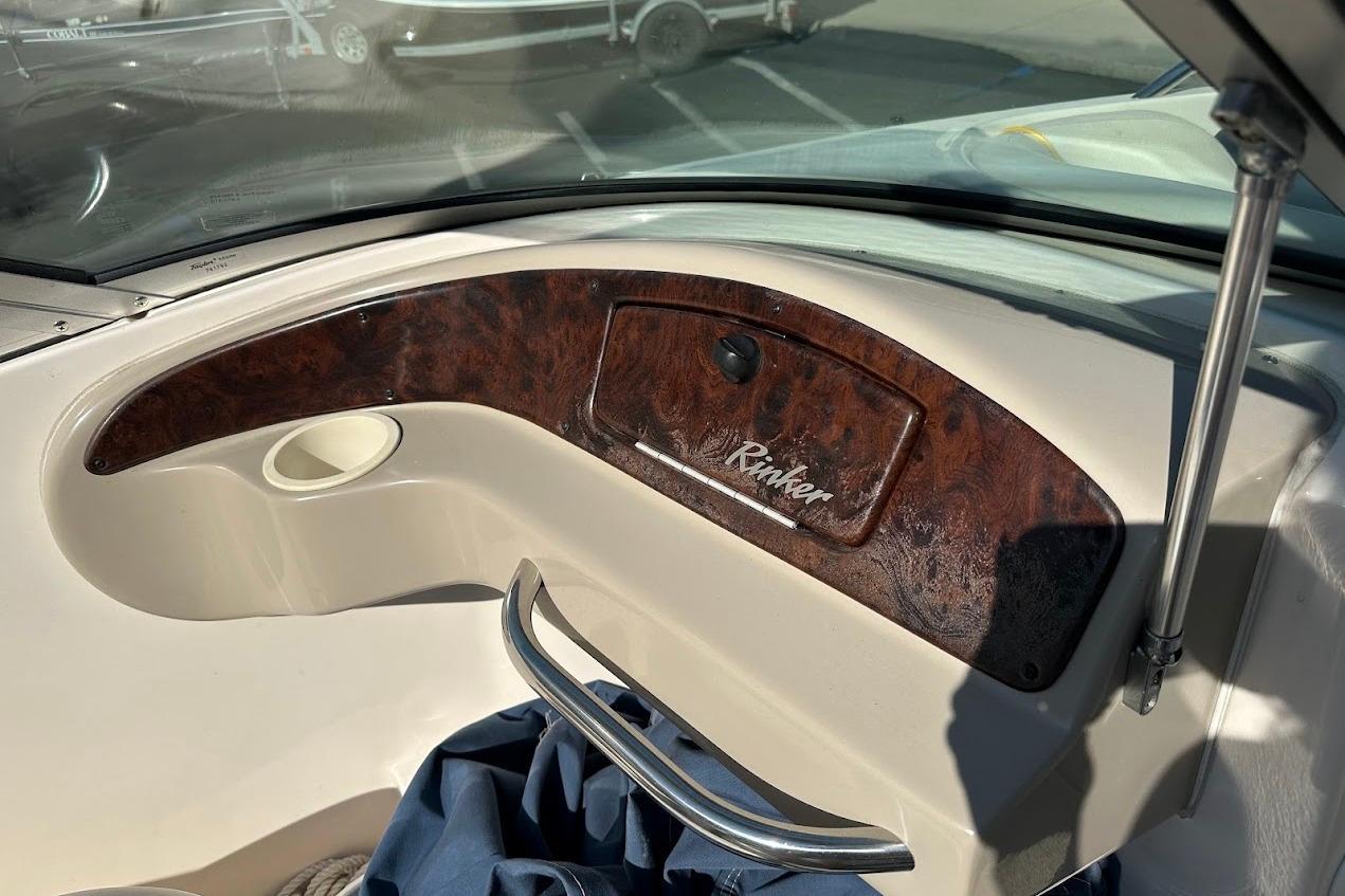 2002 Rinker 212 Captiva boat dashboard with wood paneling and storage compartment.