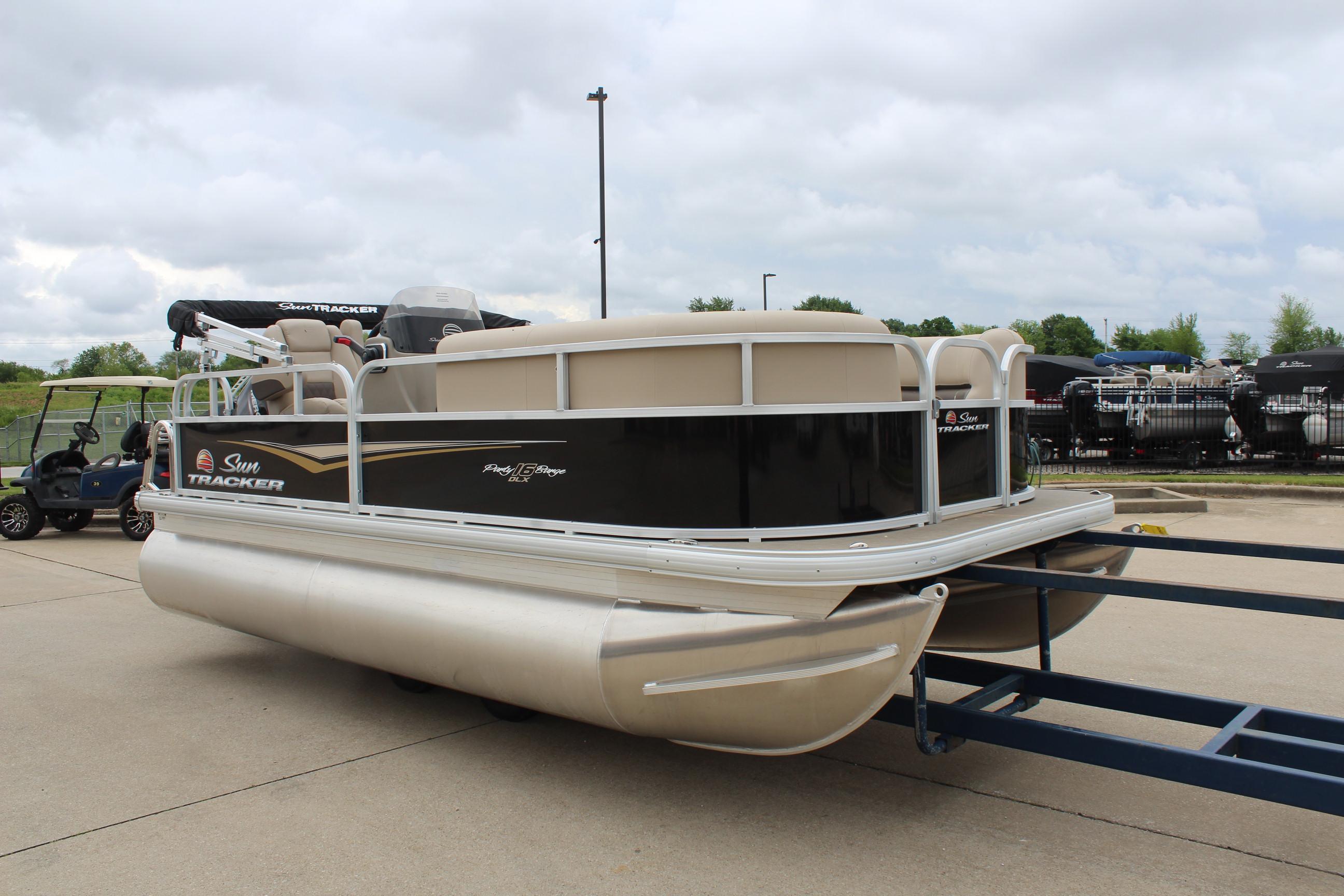 2025 Sun Tracker Party Barge 16 DLX pontoon boat on trailer, parked outdoors.