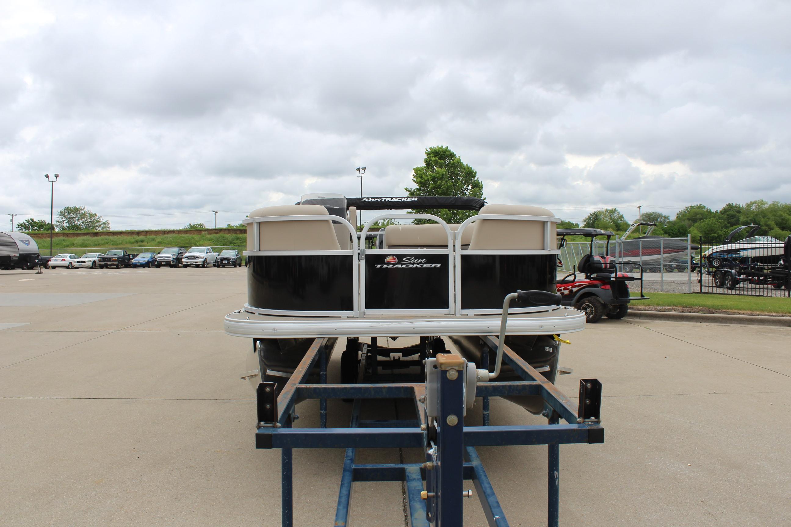 2025 Sun Tracker Party Barge 16 DLX on trailer, parked outdoors under cloudy sky.