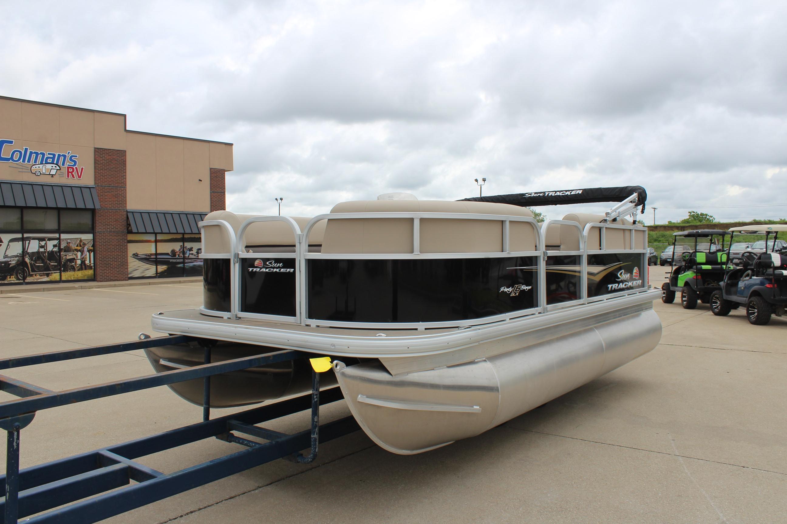 2025 Sun Tracker Party Barge 16 DLX pontoon boat on trailer at dealership.