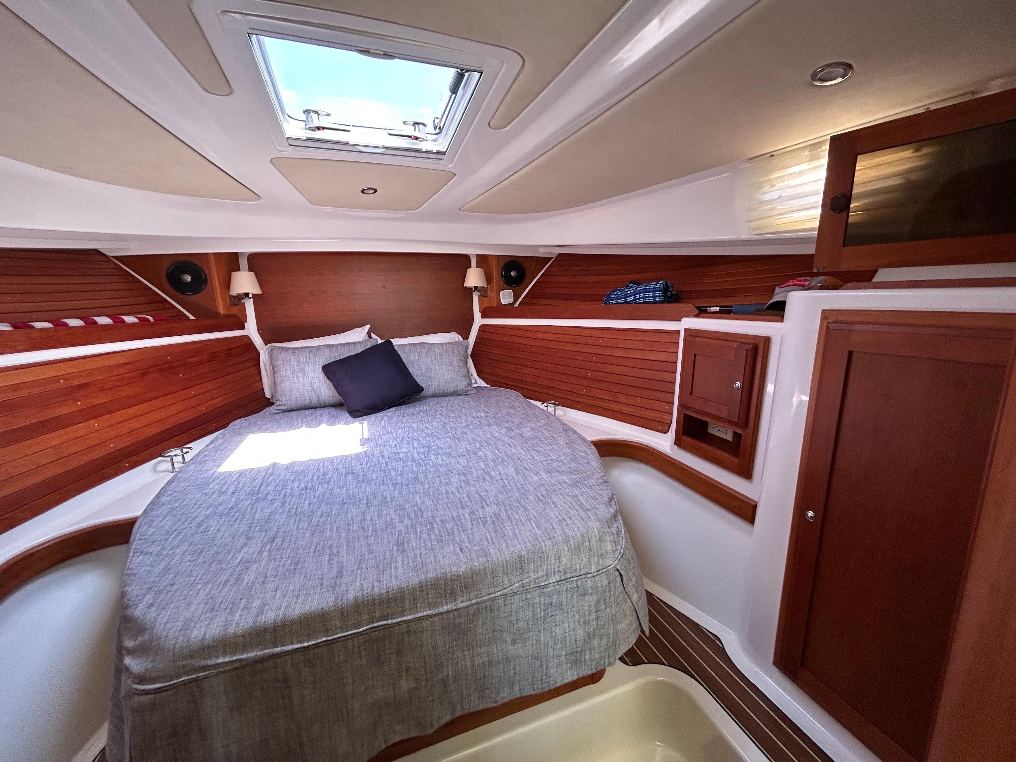 2018 Back Cove 32 cabin interior with cozy bed, wooden accents, and overhead skylight.