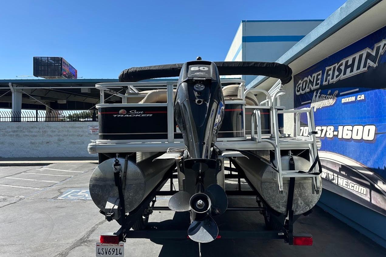 2019 Sun Tracker Bass Buggy 18 DLX pontoon boat with outboard motor, parked at dealership.