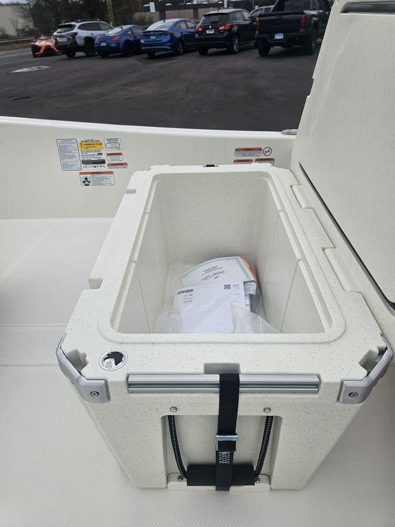2025 Mako Pro Skiff 15 CC boat storage compartment with latch, parked cars in background.