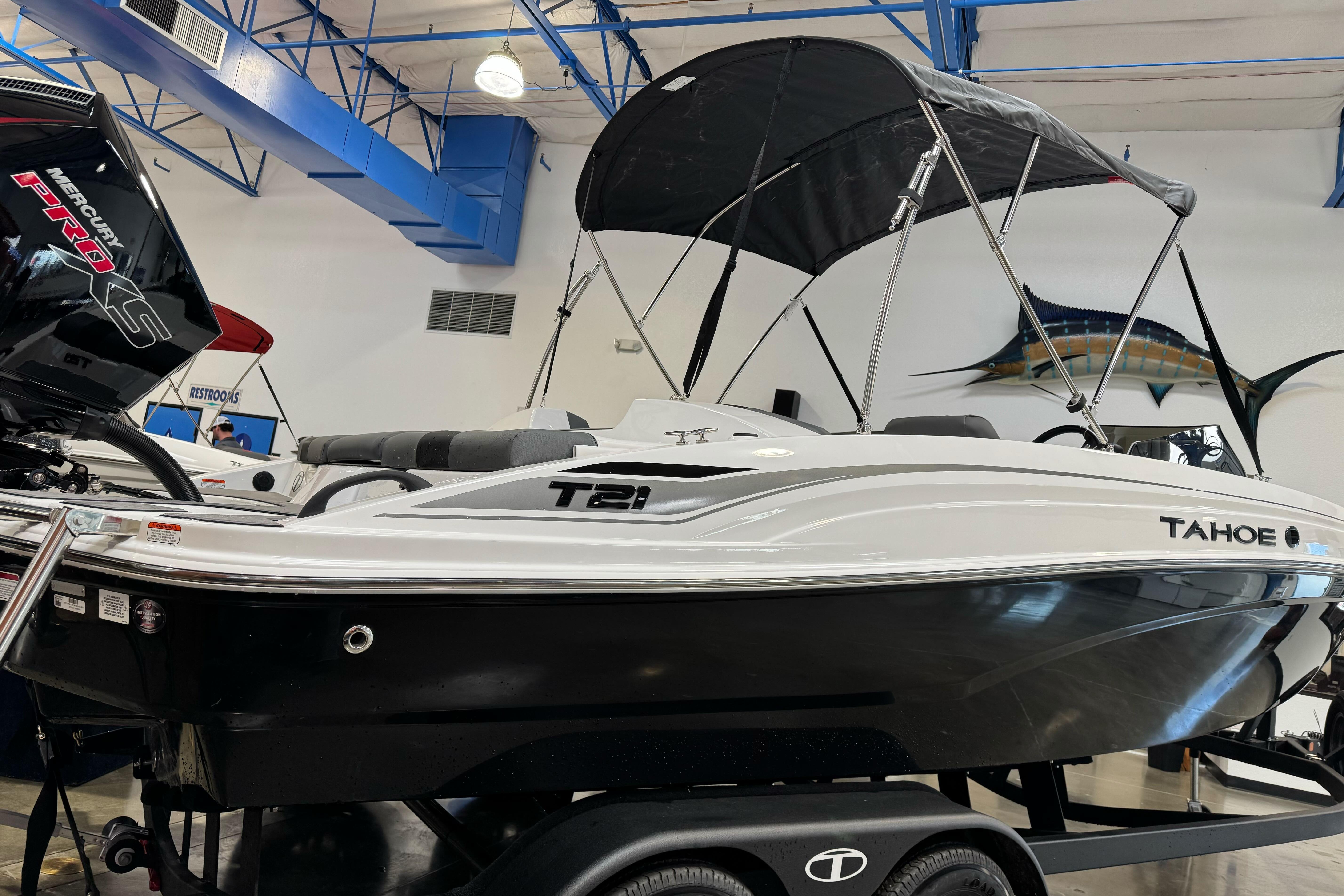 2026 Tahoe T21 boat with canopy displayed indoors, featuring sleek design and Mercury Pro S engine.