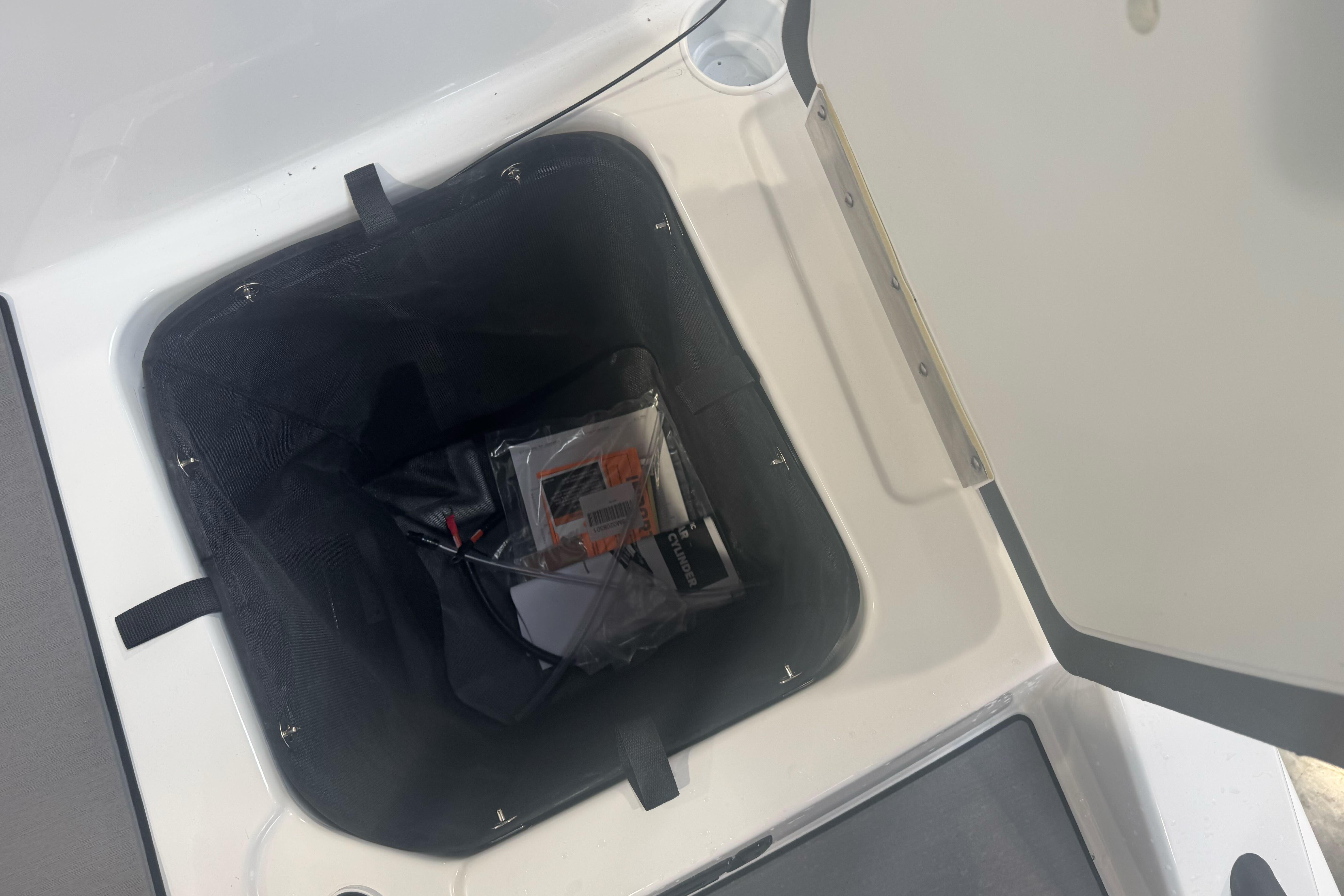Open storage compartment in 2026 Tahoe T21 boat, showing interior contents.