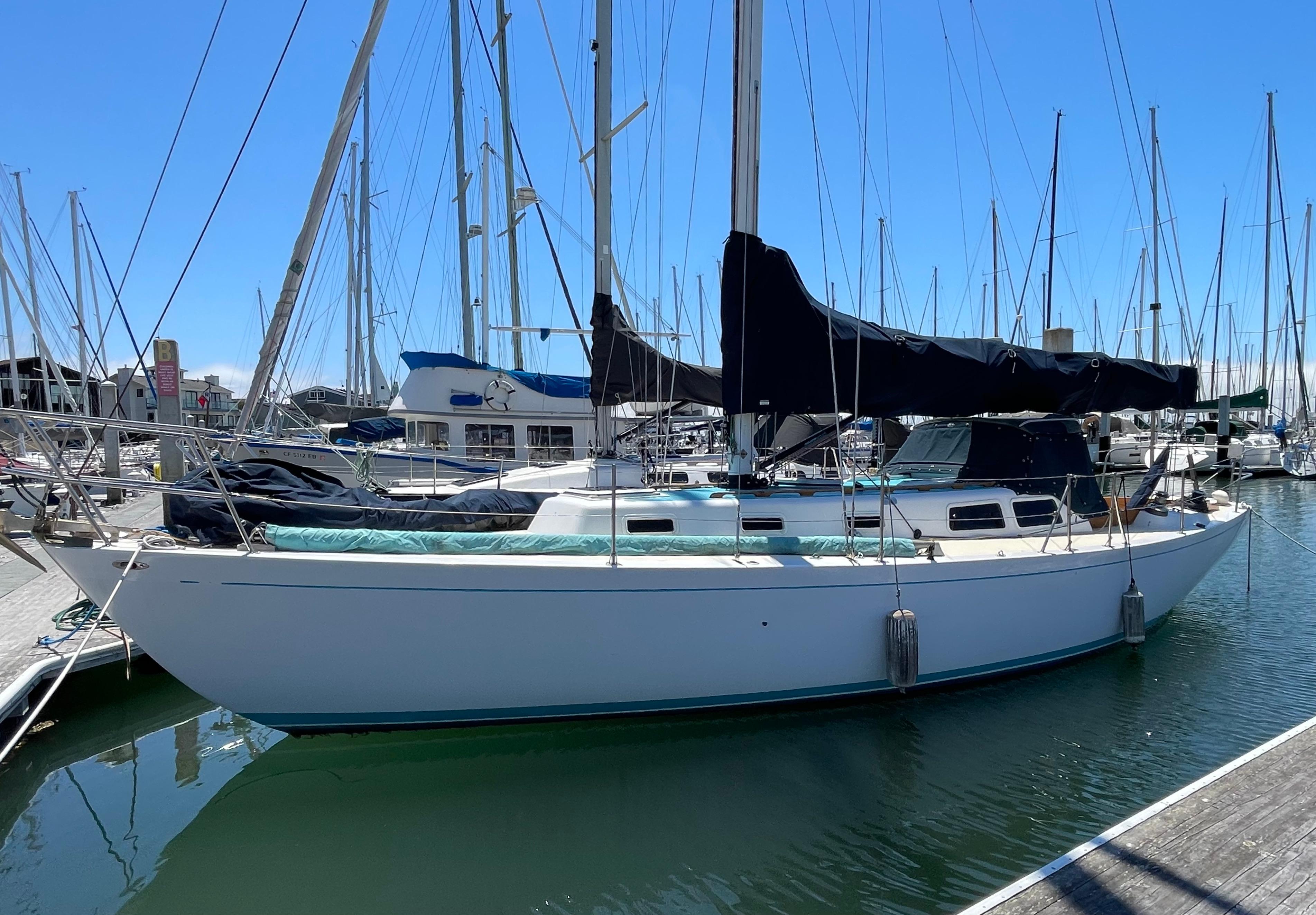 1964 CAL 40 sailboat docked at marina, surrounded by other boats under clear blue sky.
