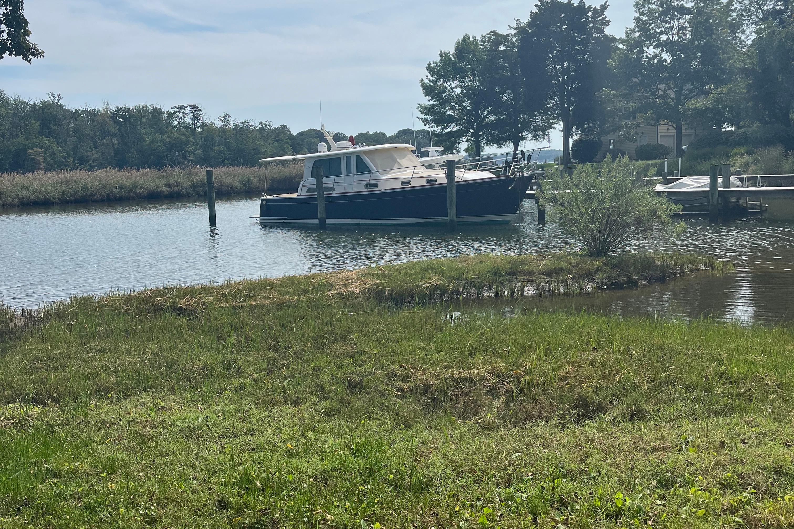 2012 Sabre 42 Salon Express yacht docked in a serene, tree-lined waterway.