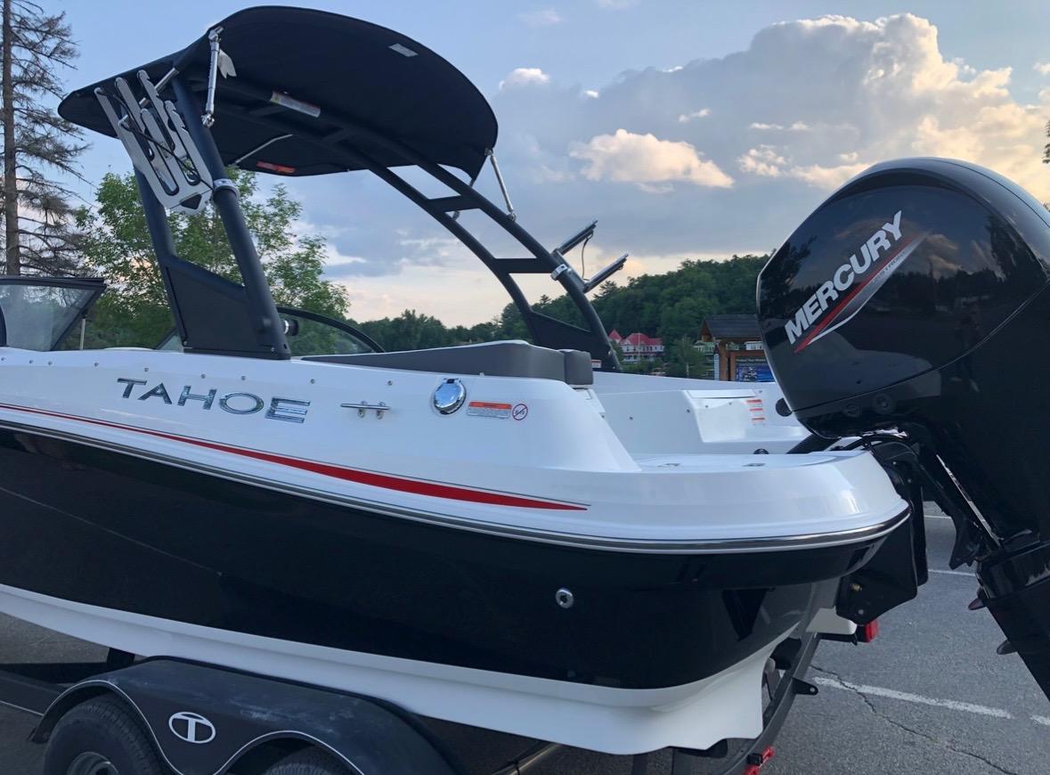 2021 Tahoe 550 TF boat with Mercury engine on trailer, parked outdoors.