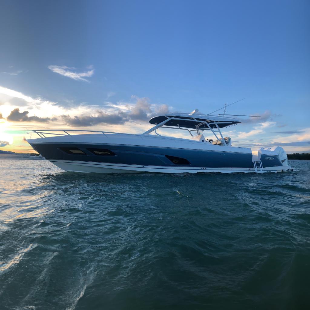 2021 Intrepid 409 Valor boat on water at sunset, showcasing sleek design and powerful engines.