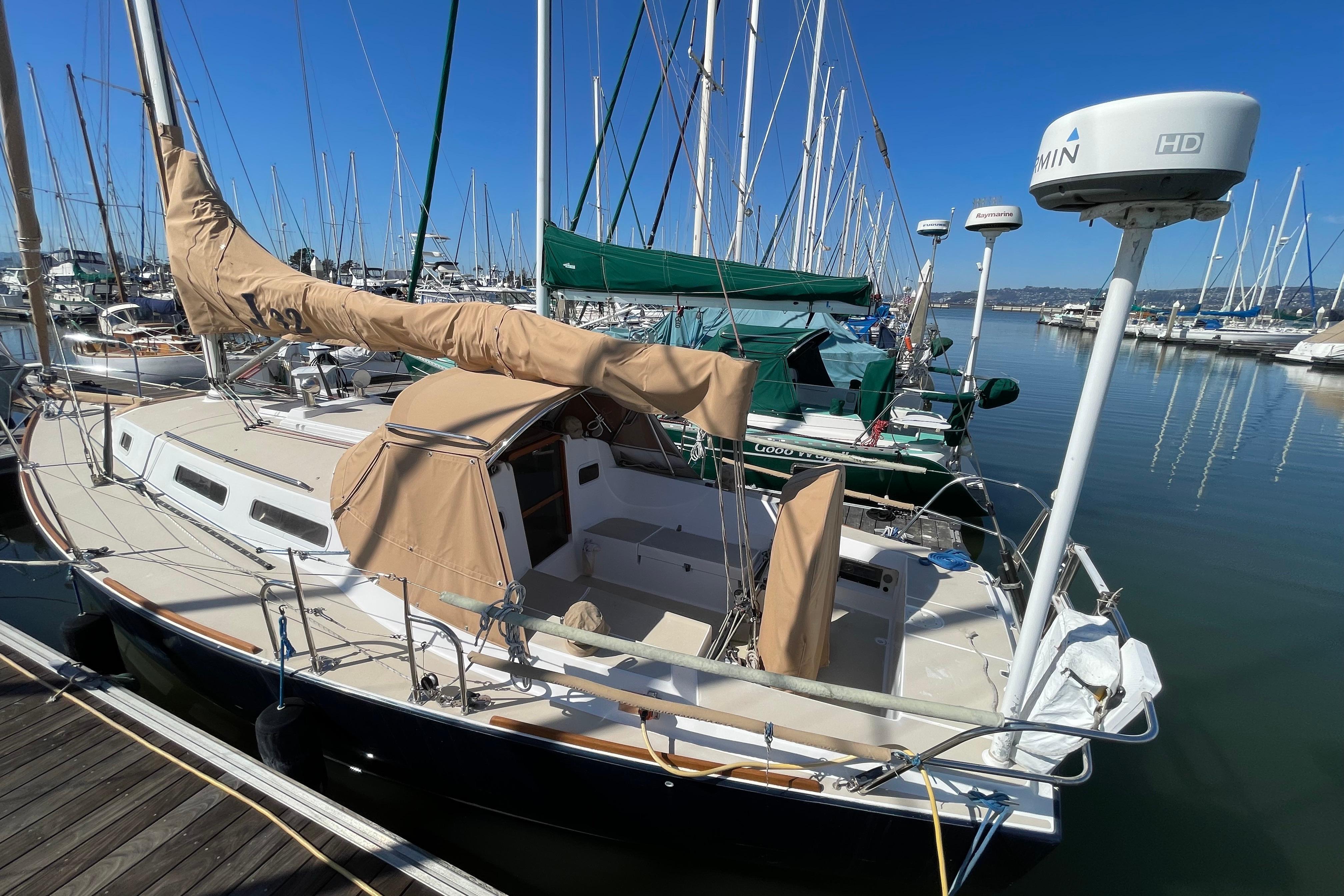 2001 J Boats J/32 sailboat docked in marina, featuring tan covers and clear blue sky.