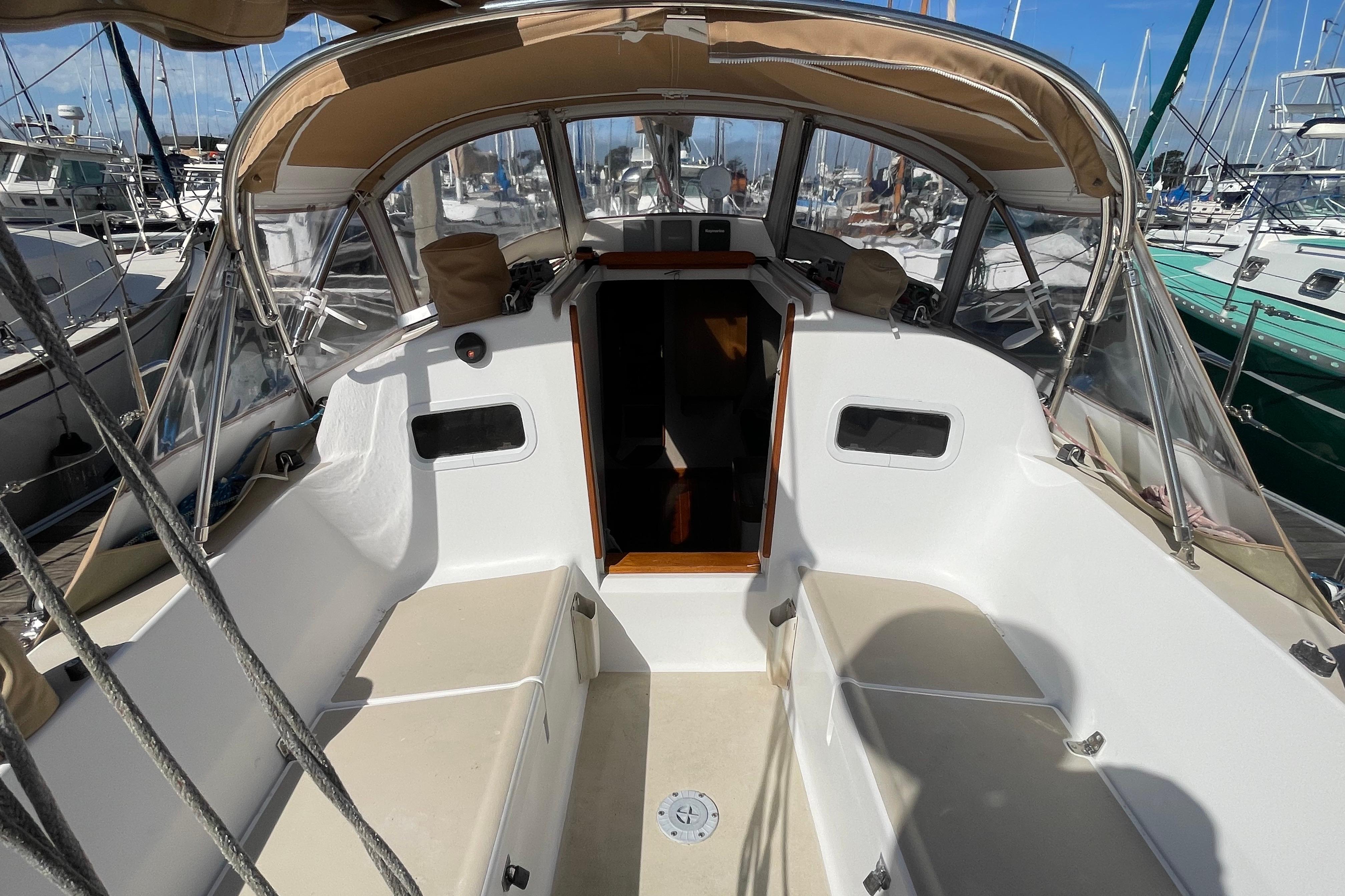 2001 J Boats J/32 sailboat cockpit with beige canopy and seating at marina.