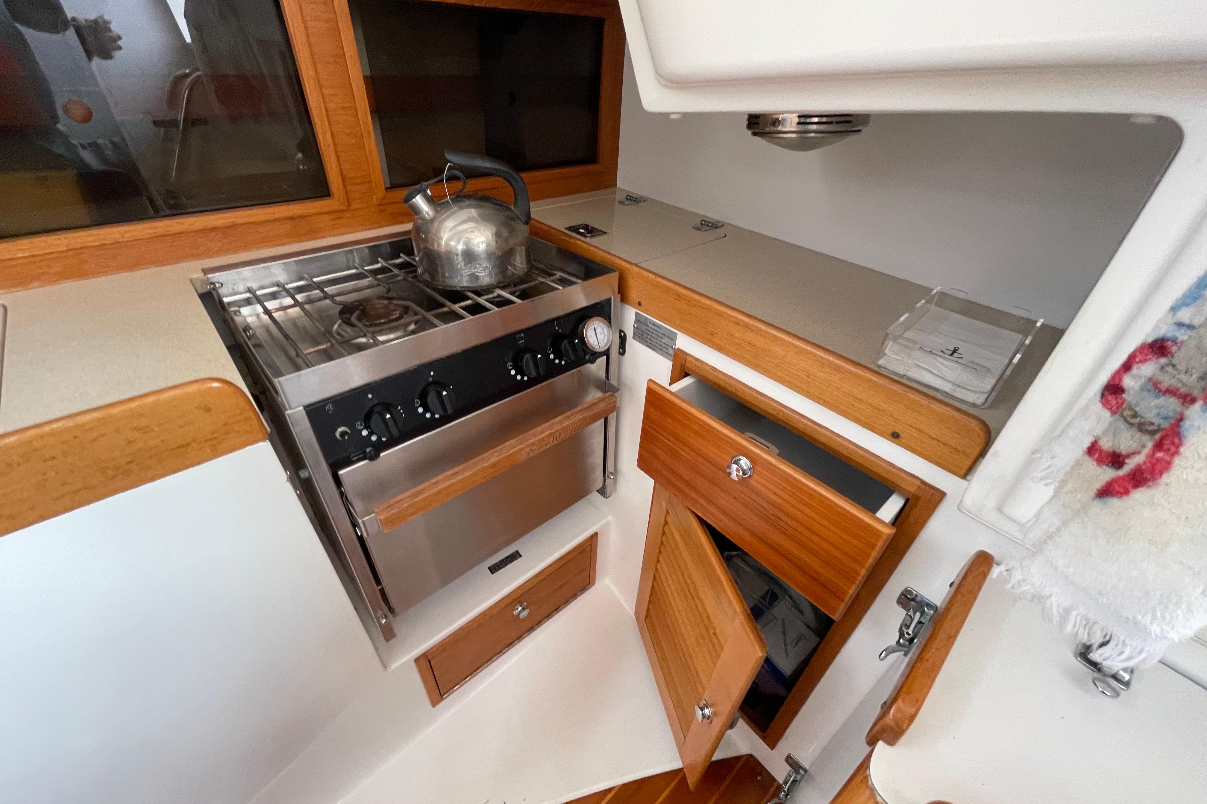 2001 J Boats J/32 yacht kitchen with stove, kettle, and wooden cabinetry.