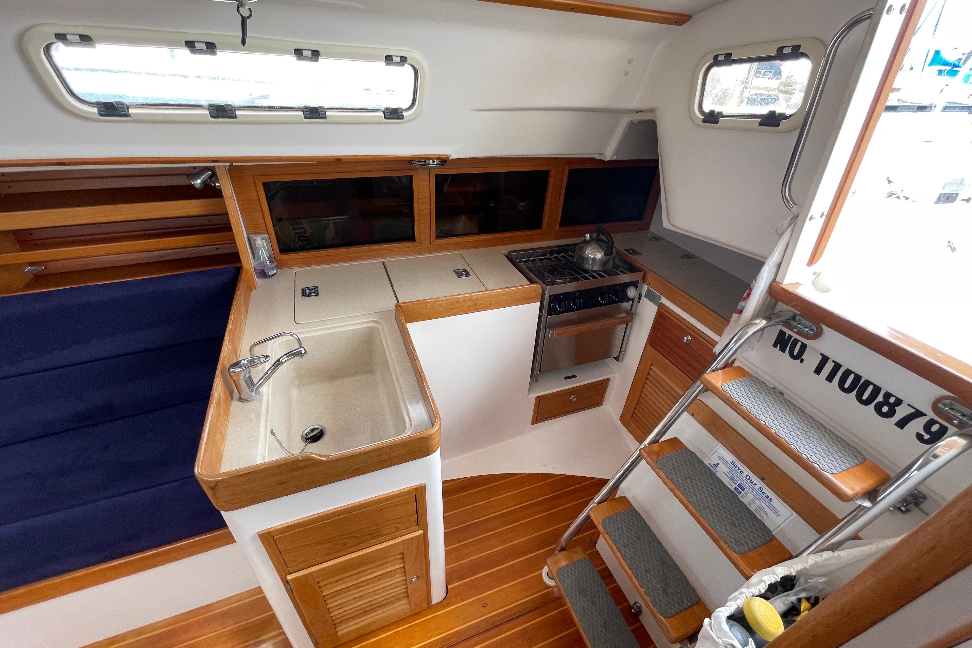 2001 J Boats J/32 interior with compact kitchen, sink, stove, and wooden cabinetry.