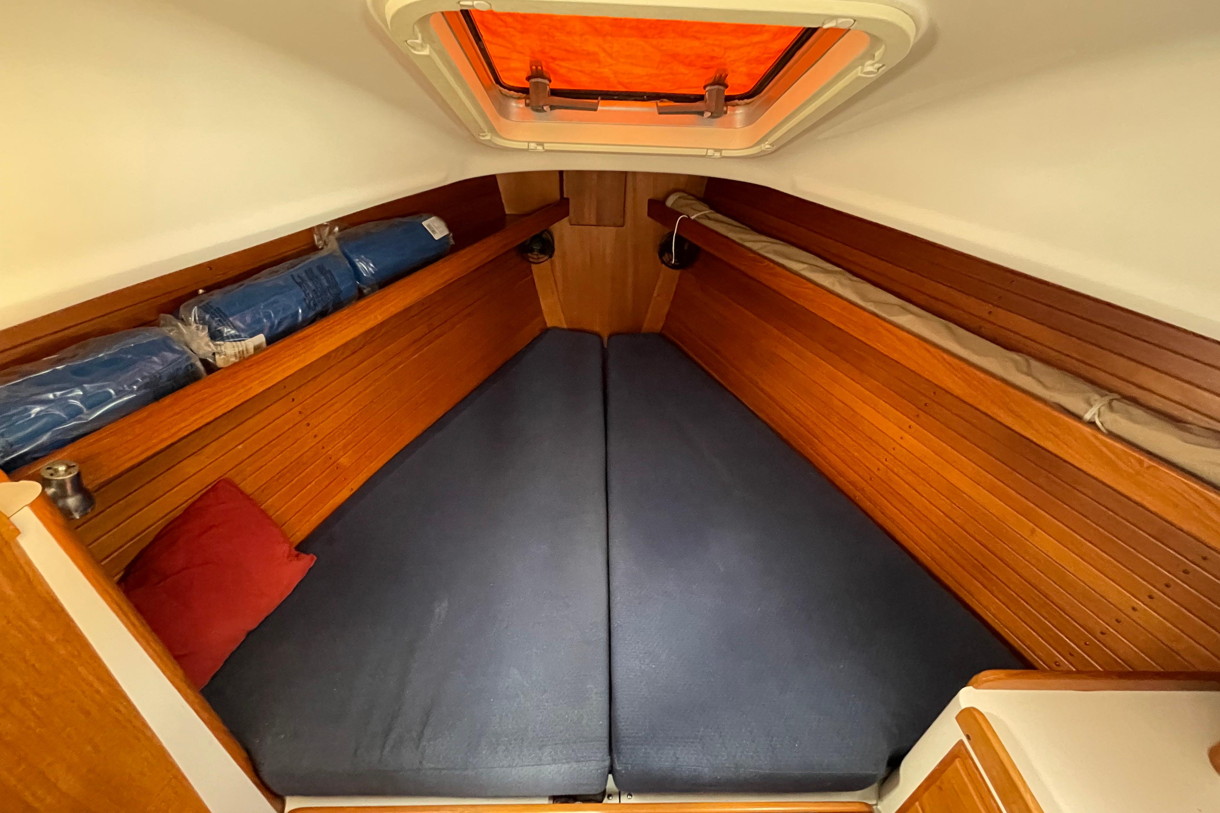 Cozy cabin interior of 2001 J Boats J/32 with wooden paneling and blue cushions.