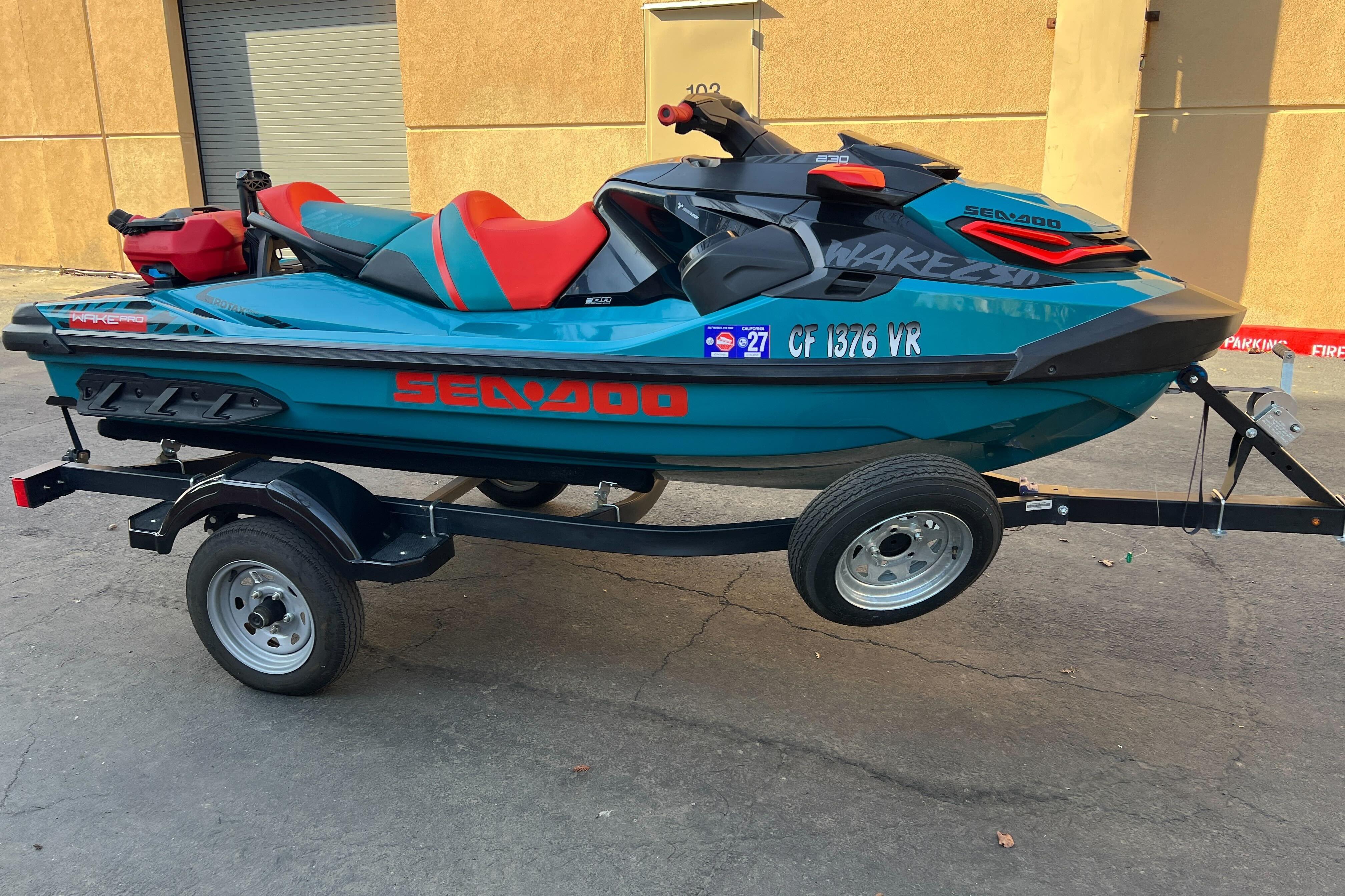 2018 Sea-Doo Wake Pro 230 on trailer, teal and red design, parked outdoors.