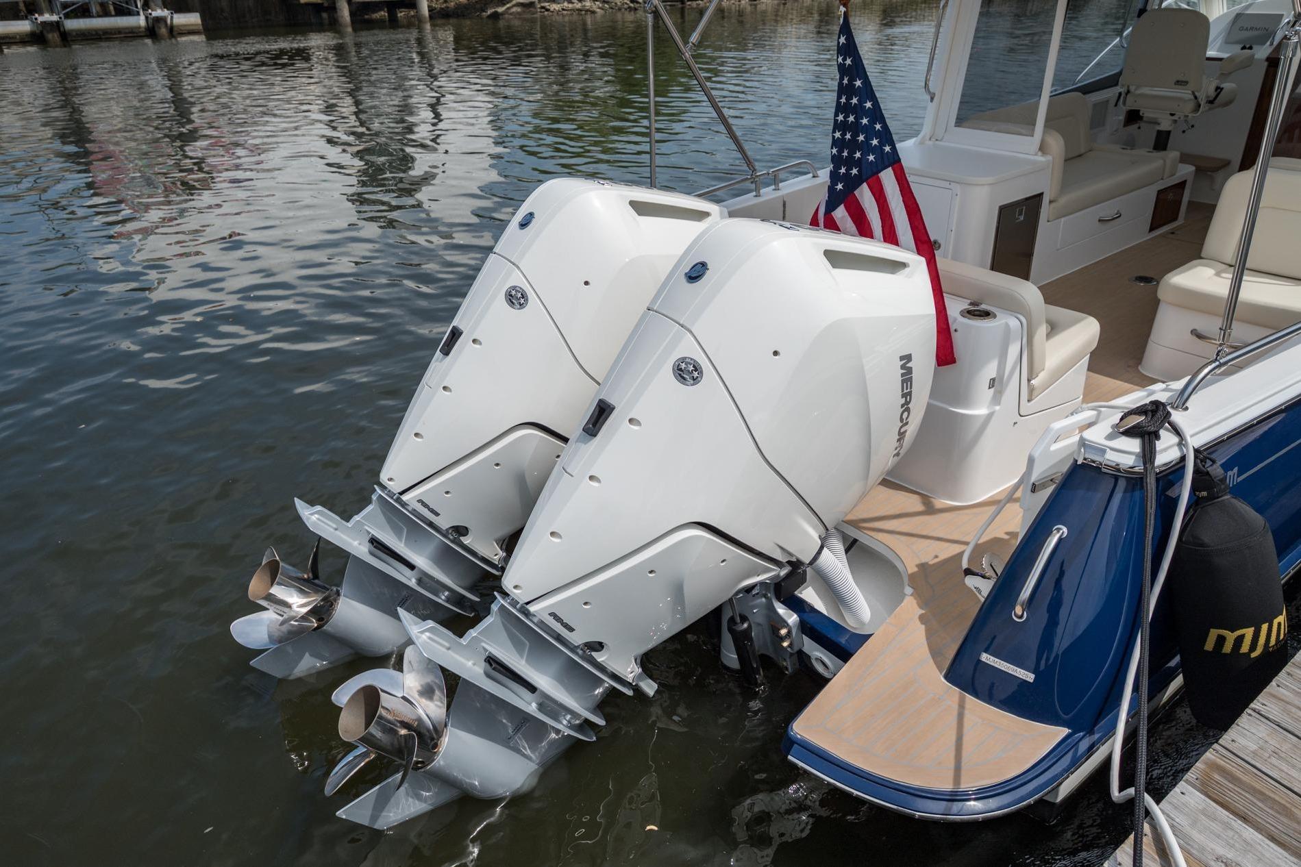 2025 MJM 35 boat with dual Mercury outboard engines and American flag on water.