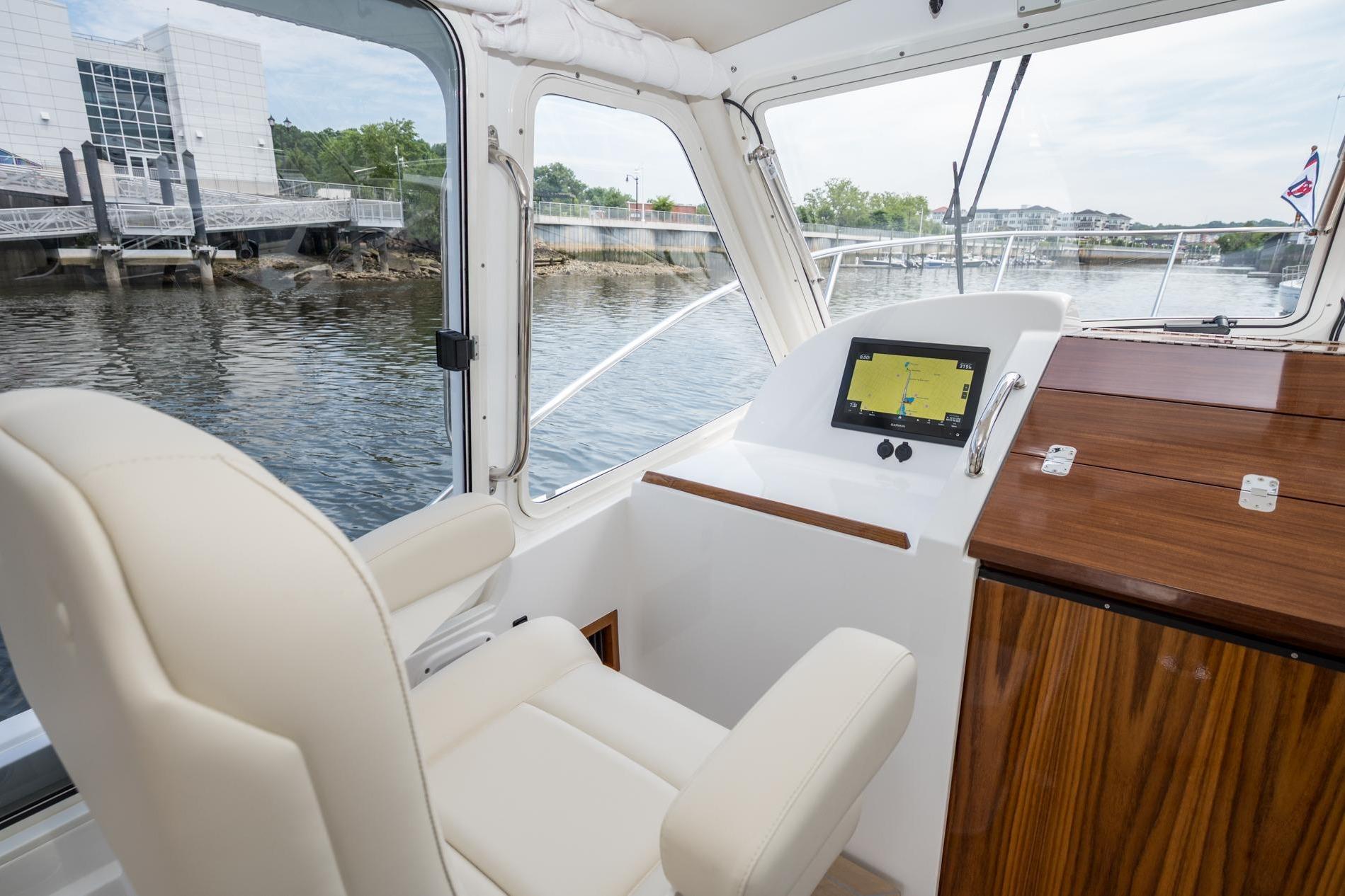 Interior of 2025 MJM 35 boat with helm, navigation screen, and waterfront view.