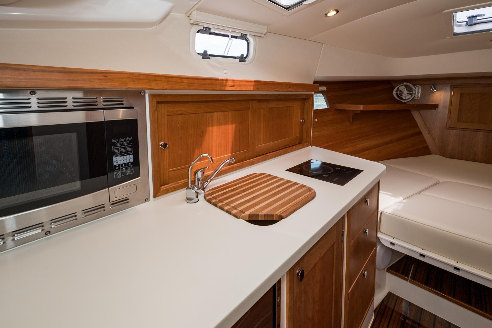 Modern kitchen interior of 2025 MJM 35 yacht with wood cabinetry and appliances.