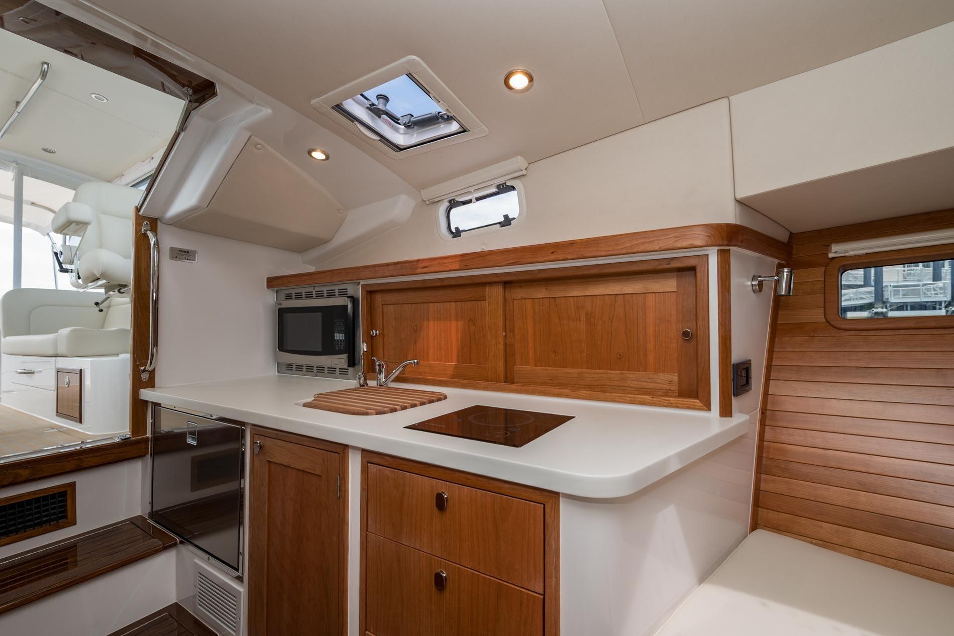 Modern kitchen interior of 2025 MJM 35 yacht with wood accents and appliances.