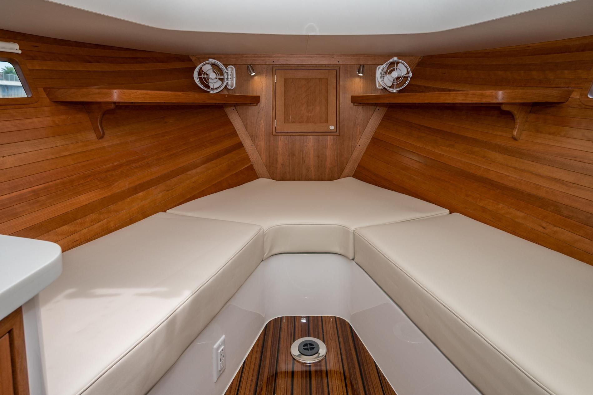 Luxurious interior of 2025 MJM 35 boat with wooden finish and cushioned seating.