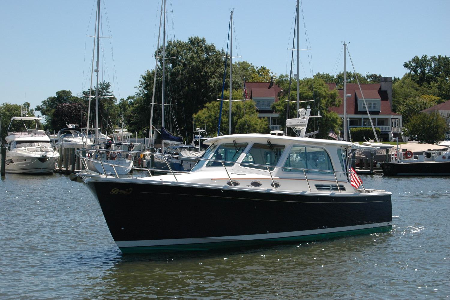 2014 Back Cove 37 boat docked in a marina with surrounding sailboats and waterfront homes.