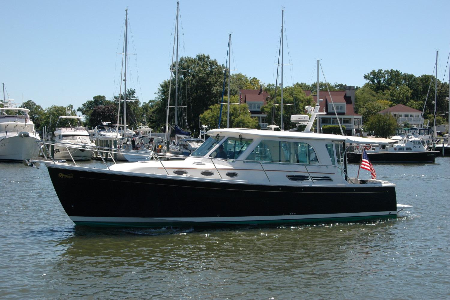 2014 Back Cove 37 yacht cruising in a marina with sailboats and waterfront homes.