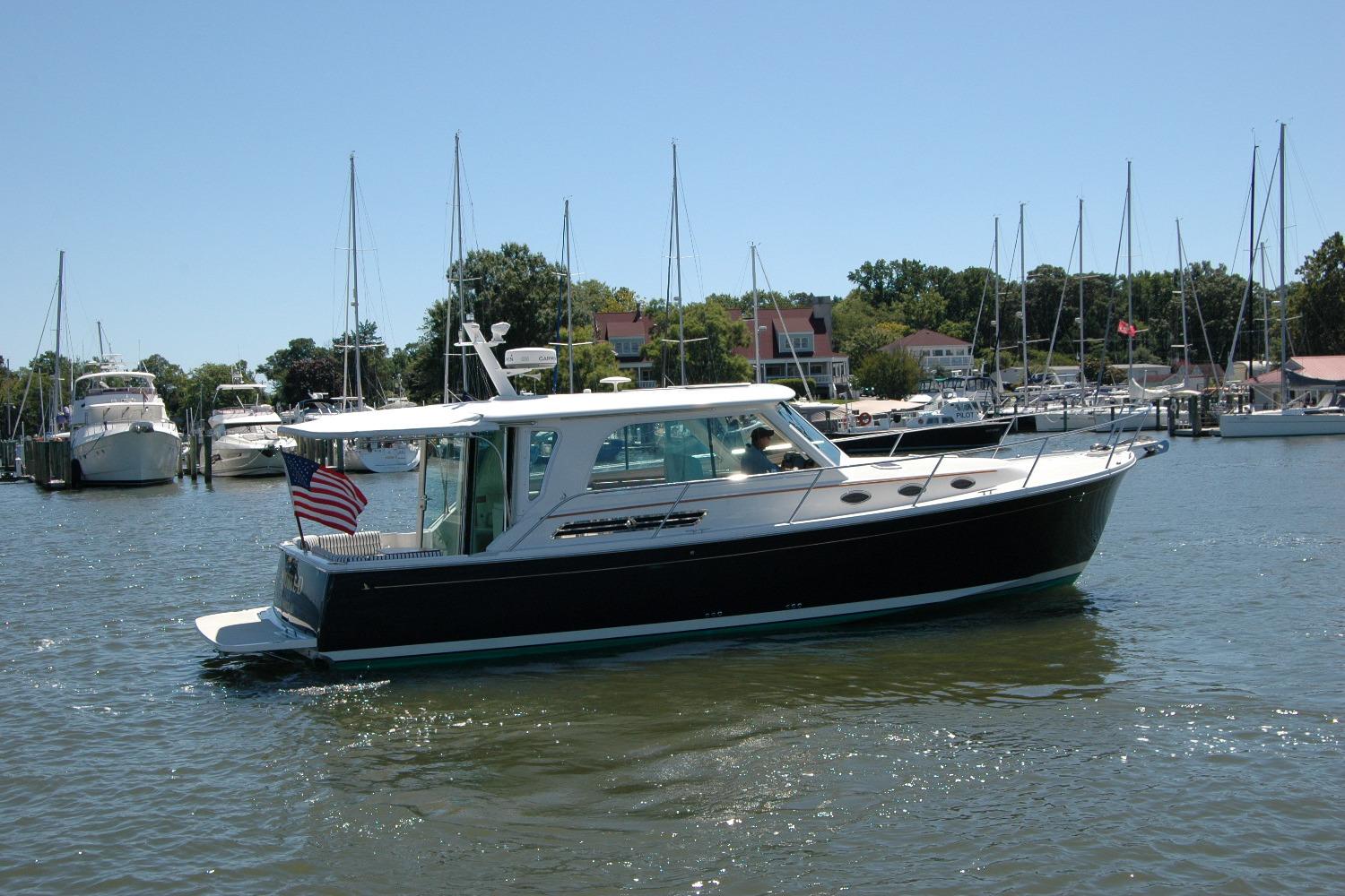2014 Back Cove 37 boat cruising in a marina with sailboats in the background.