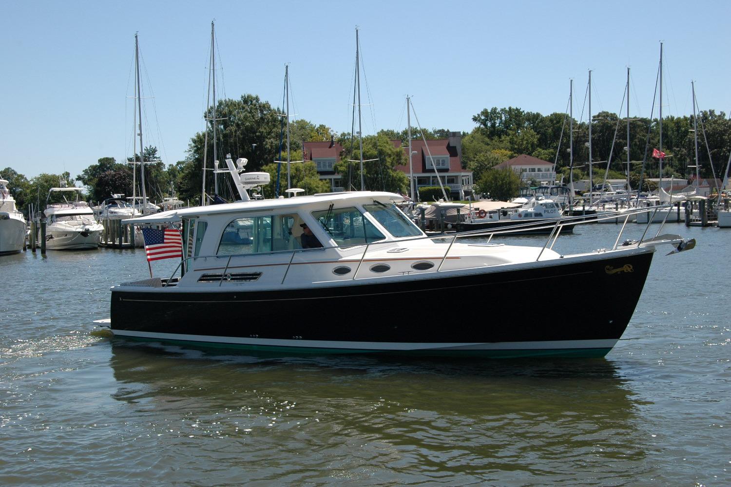 2014 Back Cove 37 boat cruising in a marina with sailboats and waterfront homes.