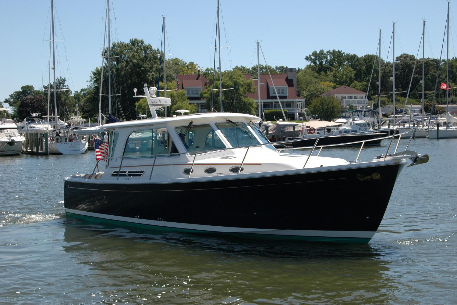 2014 Back Cove 37 boat cruising in a marina with sailboats and waterfront homes.