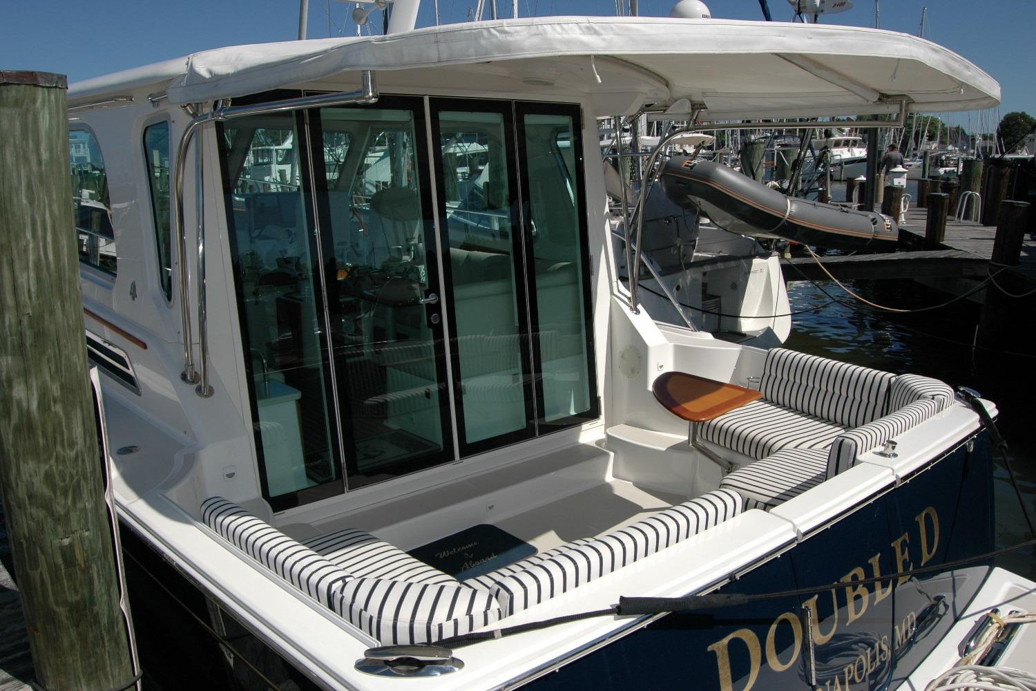 2014 Back Cove 37 yacht with striped seating and glass doors at a marina.