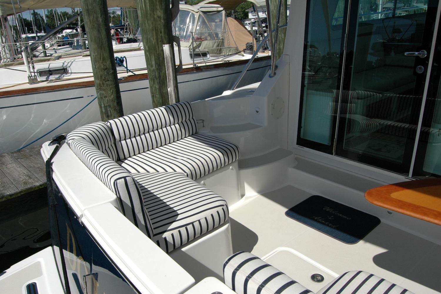 2014 Back Cove 37 yacht with striped seating and wooden table in the cockpit area.