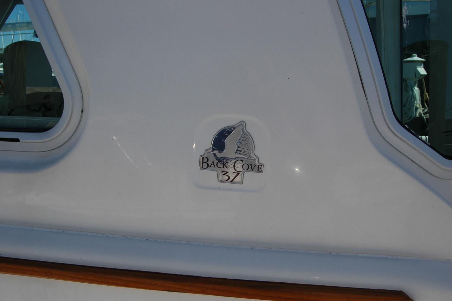2014 Back Cove 37 boat logo on white exterior near window.