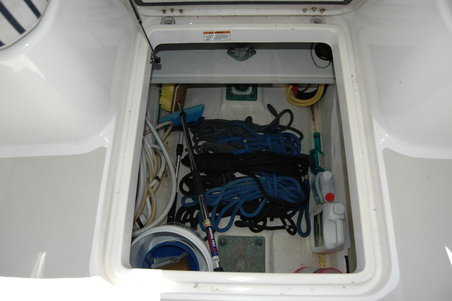 Storage compartment on a 2014 Back Cove 37 boat with ropes and cleaning supplies.