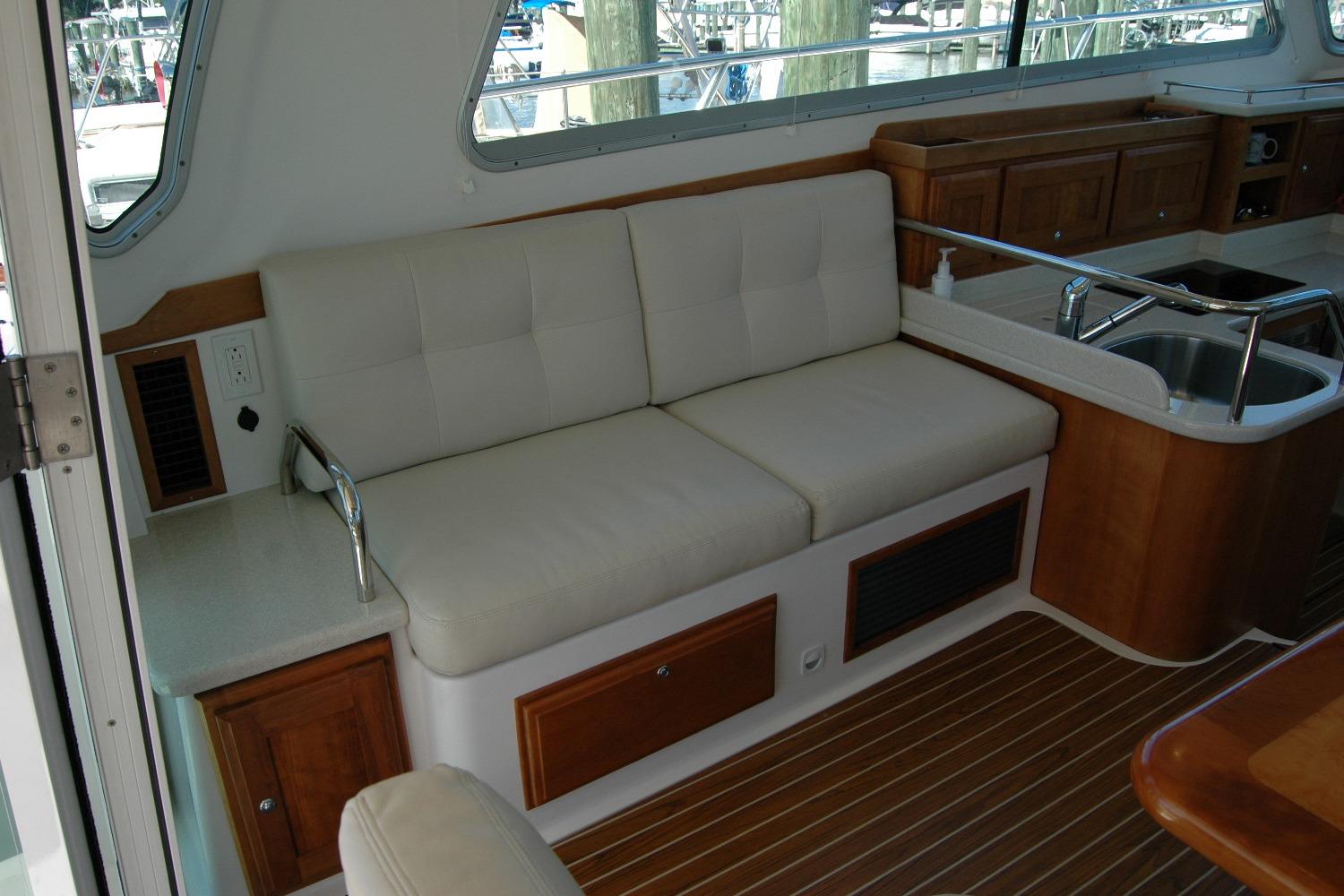 Interior of 2014 Back Cove 37 yacht with cushioned seating and wooden cabinetry.