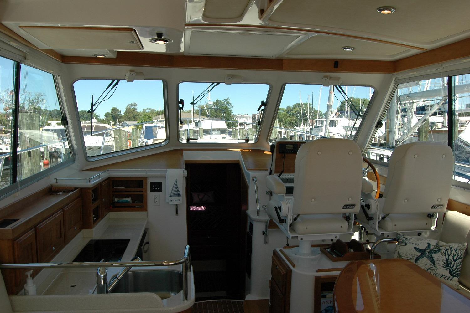 Interior of 2014 Back Cove 37 yacht with helm, seating, and windows overlooking marina.