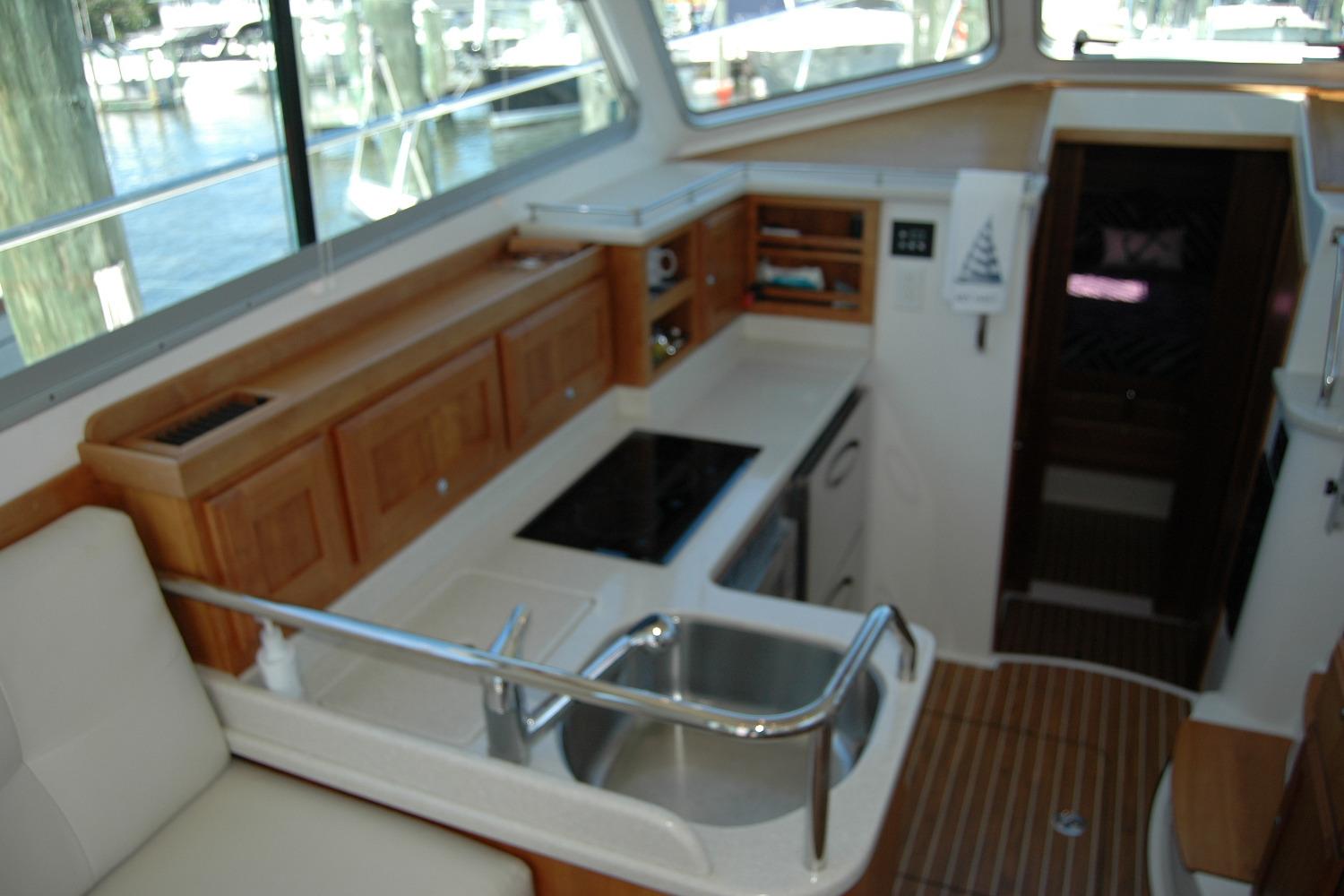 Interior of 2014 Back Cove 37 yacht, featuring a compact kitchen with wooden cabinetry.