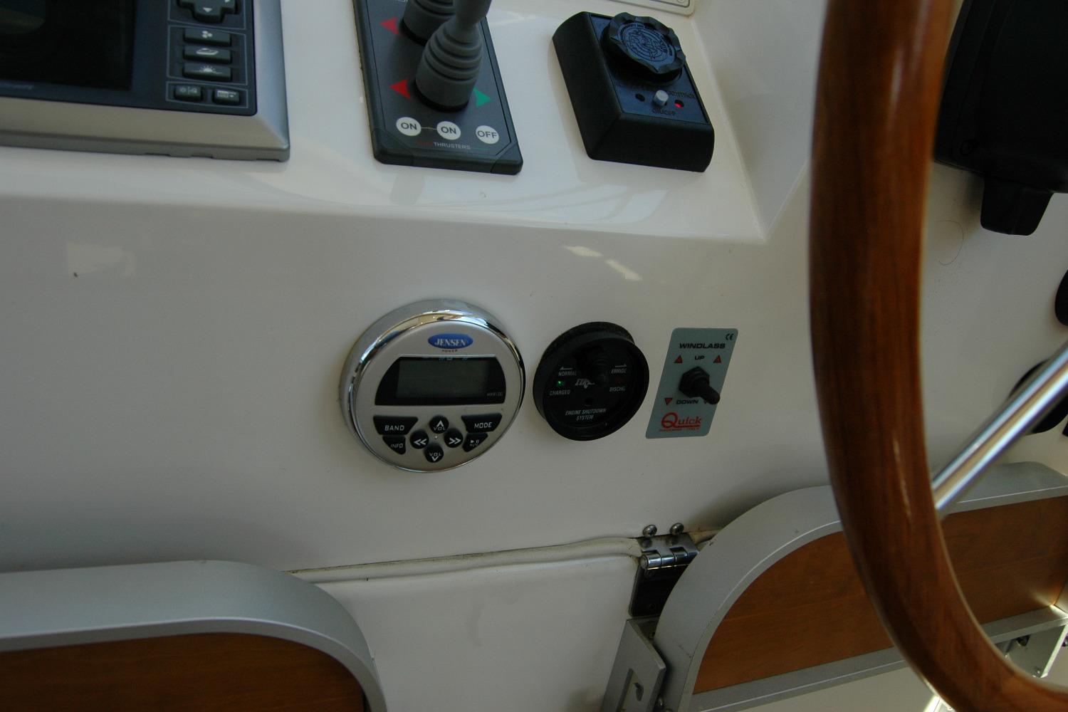 Control panel of a 2014 Back Cove 37 boat, featuring various instruments and a wooden steering wheel.